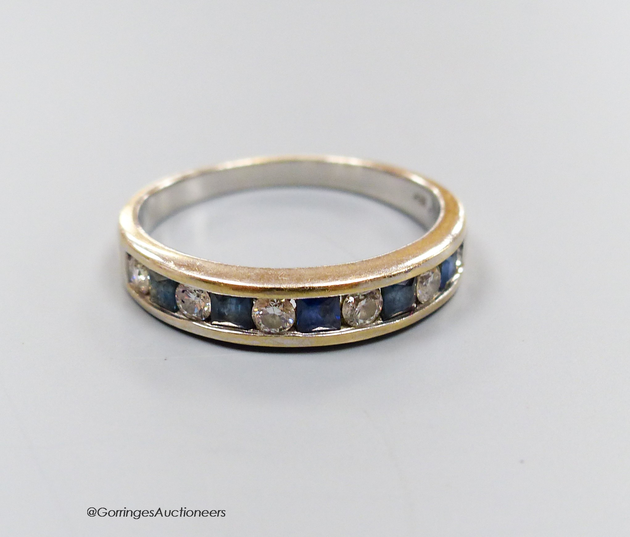 An 18ct white gold channel set six stone diamond and five stone sapphire half hoop ring, size Q, gross weight 3.7 grams.